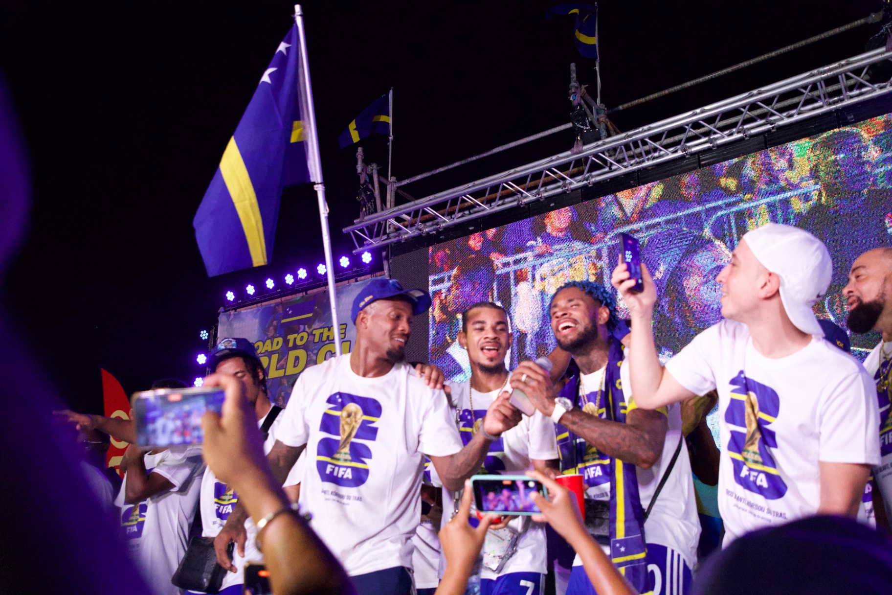 Curaçao players on stage with the crowd celebrating.
